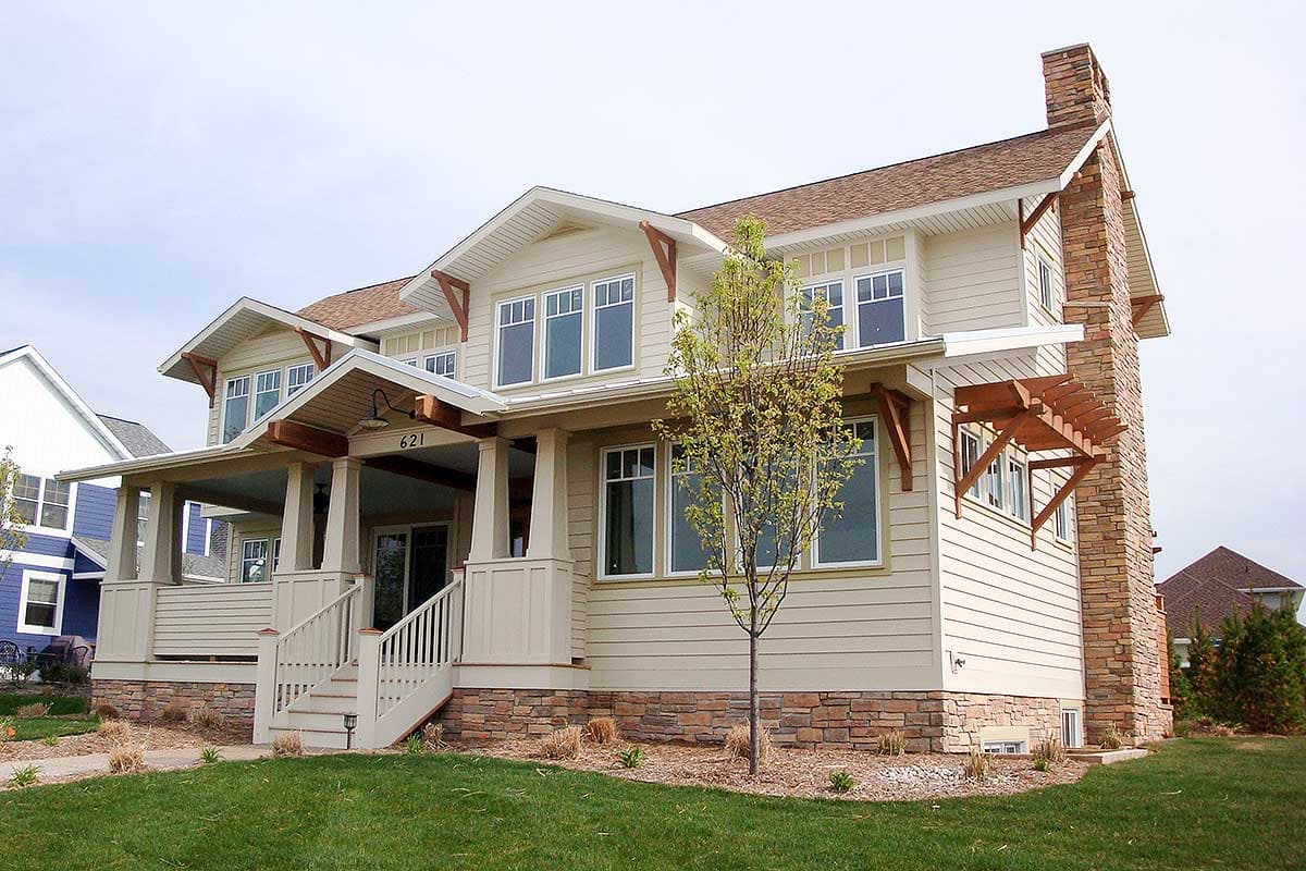 Craftsman style house plan exterior with wraparound porch, stone foundation, gables, and large chimney.