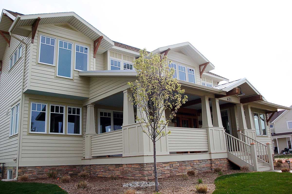 House plan exterior showing a two-story modern home with gables, decorative brackets, and a wraparound porch.