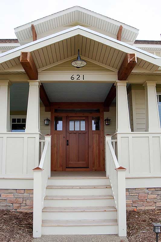 Craftsman house plan exterior with stone foundation, wood-paneled siding, covered porch, and multi-light wood door.
