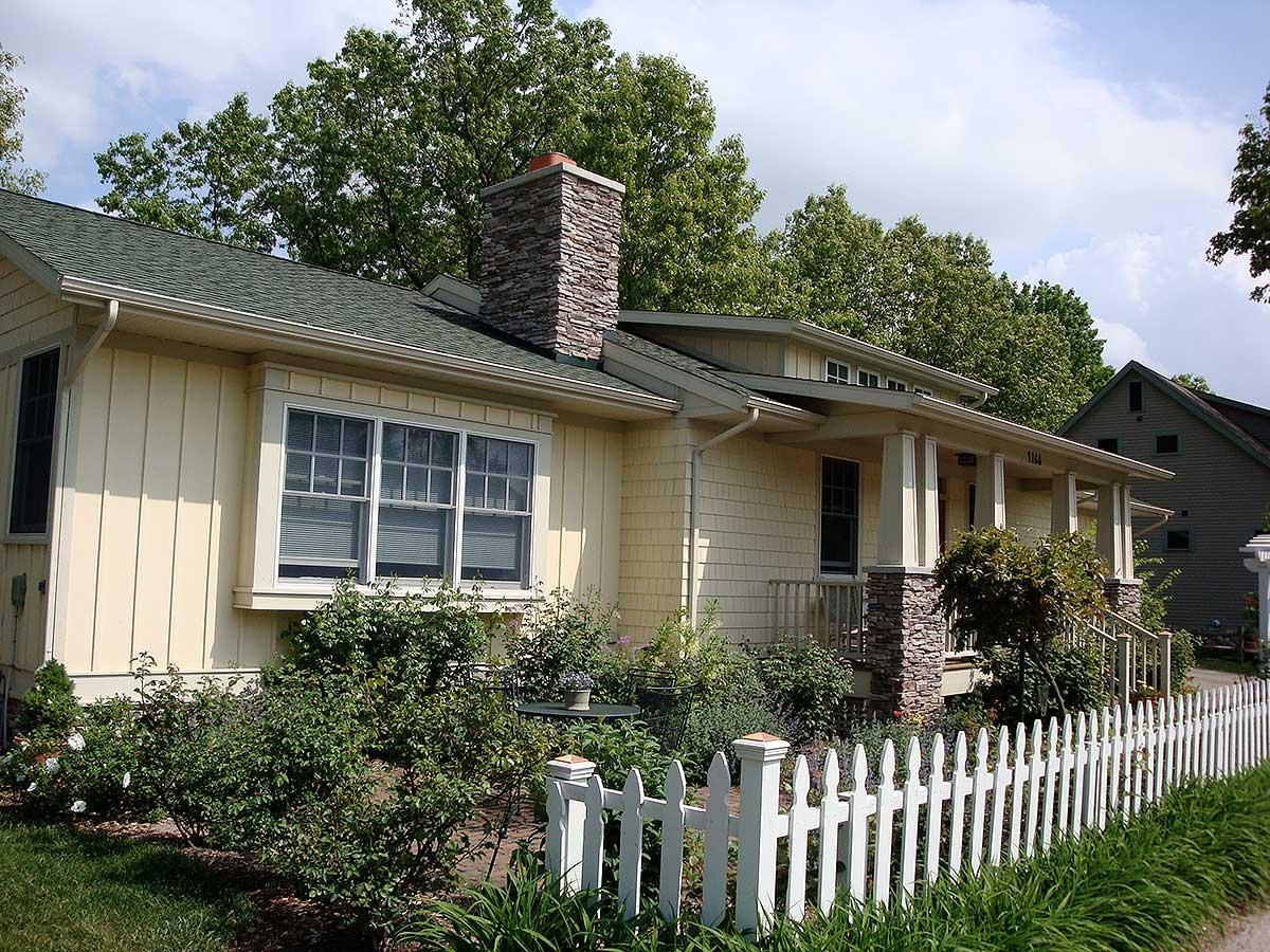 Craftsman house plan exterior with a covered porch, stone-clad pillars, and a prominent stone chimney.