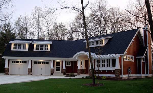 Craftsman style house plan exterior with three-car garage, dormers, arched entry, and stone and shingle siding.
