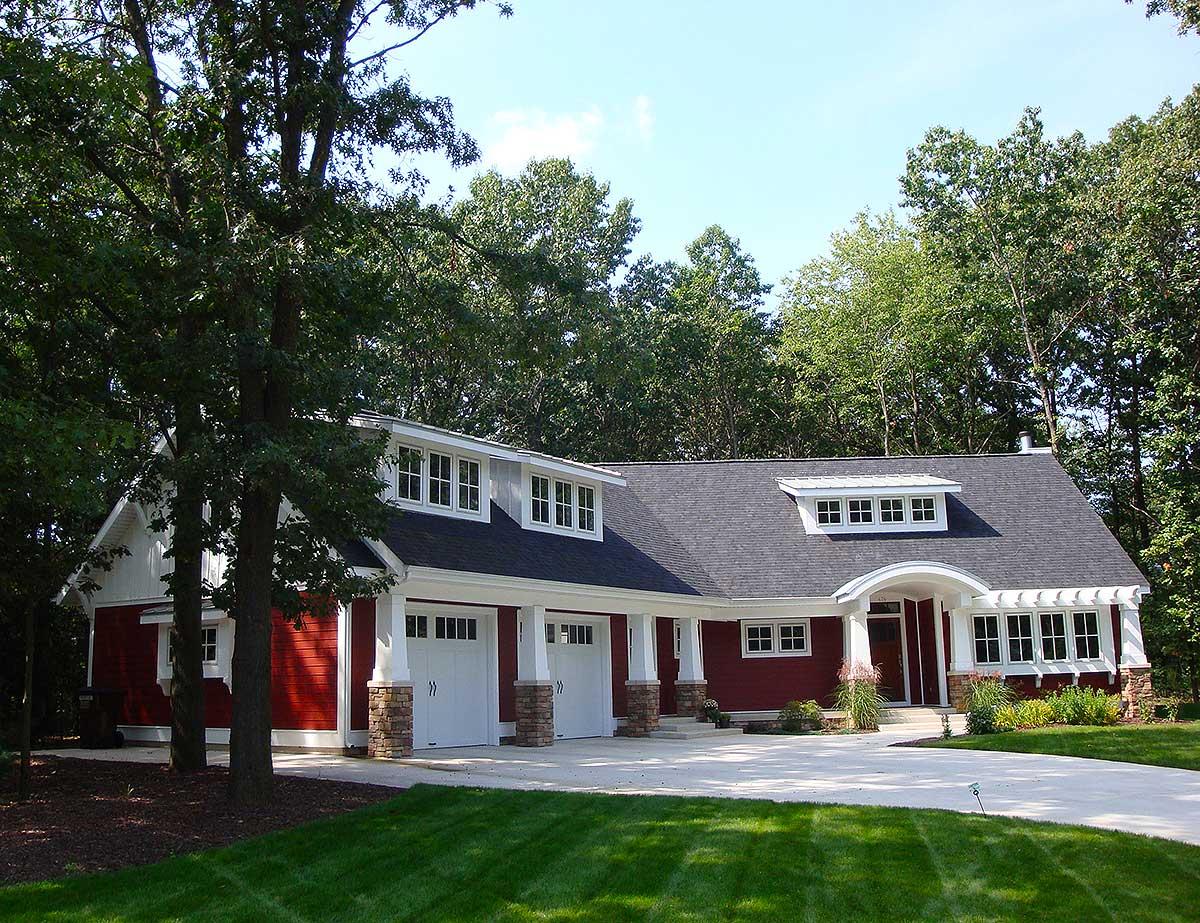 House plan exterior: Ranch style with three-car garage, dormers, and arched entry.