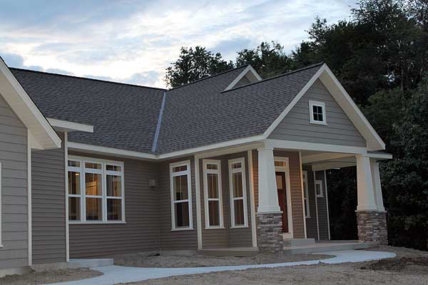 House plan exterior of a modern farmhouse style home with a covered porch, stone-clad columns, and multiple gables.