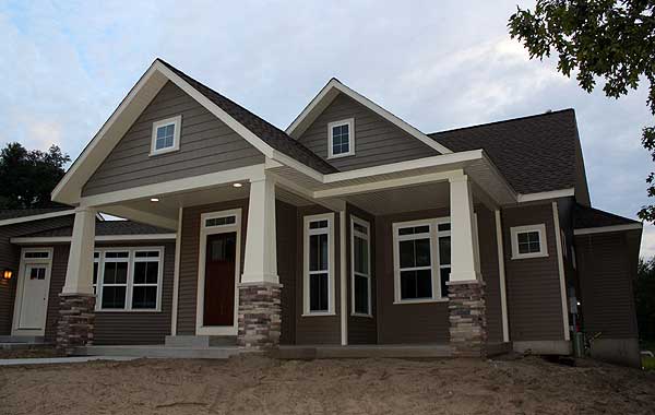 House plan exterior: Ranch style with prominent gables, covered porch supported by stone-clad columns, and multiple dormers.