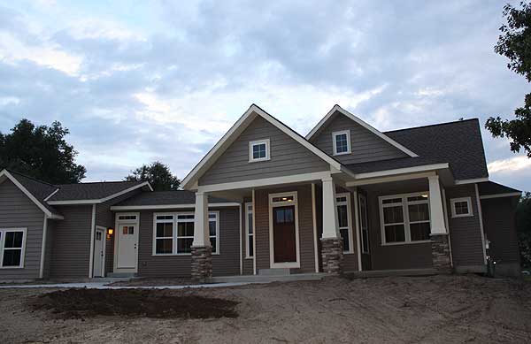 House plan exterior: Ranch style, covered front porch with stone-clad columns, multiple gables, and horizontal siding.