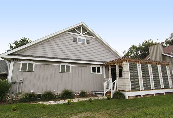 House plan exterior: One-story house with shingle siding, gables, and a covered patio with louvered shutters.