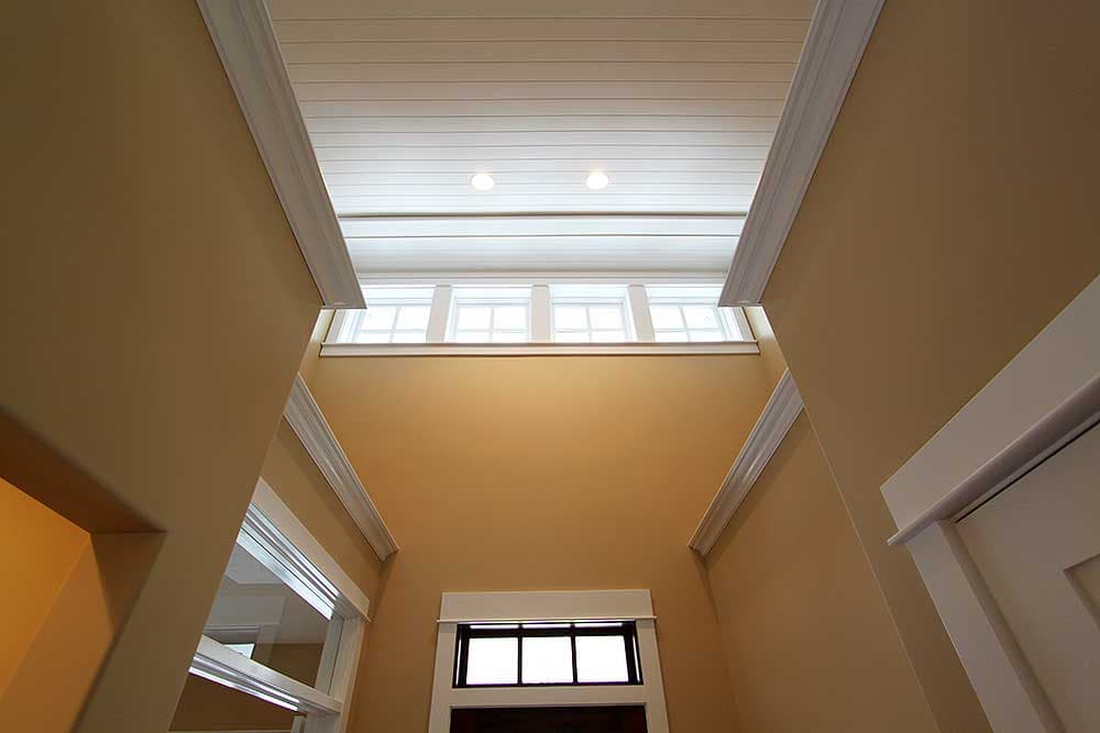 Interior view of a double-height foyer with a cased opening and a transom window above a doorway.