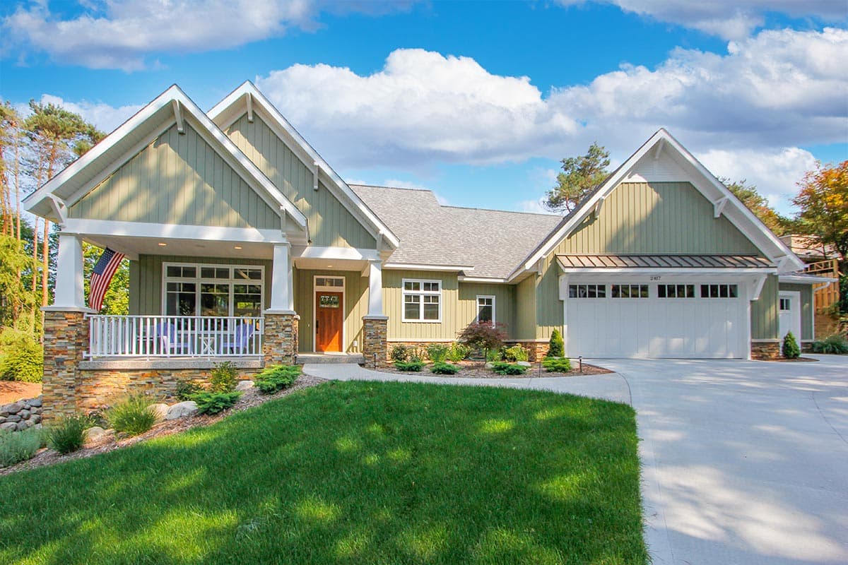 House plan exterior: Ranch style, green siding, covered porch with stone accents, and a two-car garage.