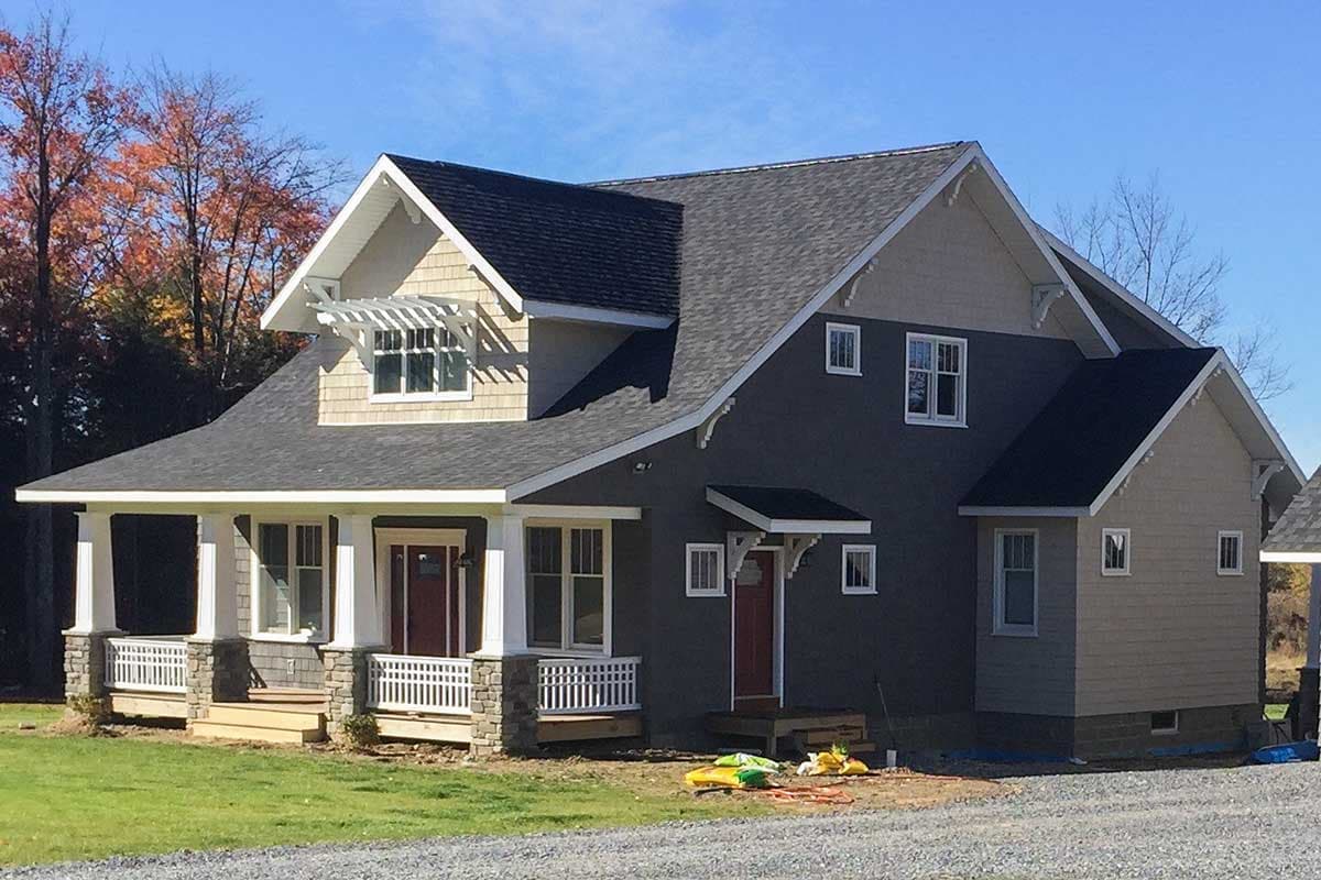 House plan exterior showing a two-story Modern Farmhouse with a covered porch, stone accents, and decorative gables.
