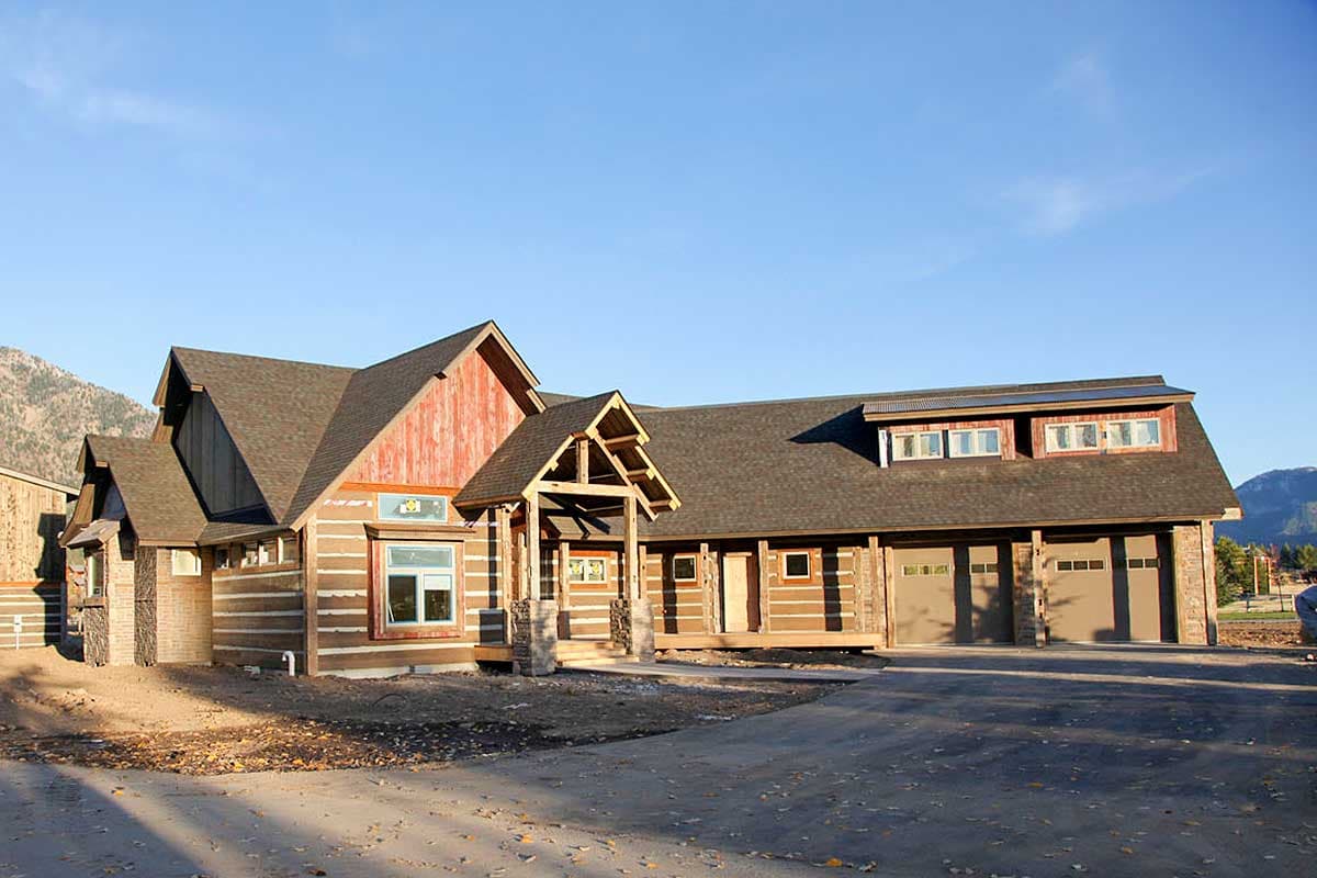 Log home exterior plan with multiple gables, covered porch, and a four-car garage under a dormer roof.