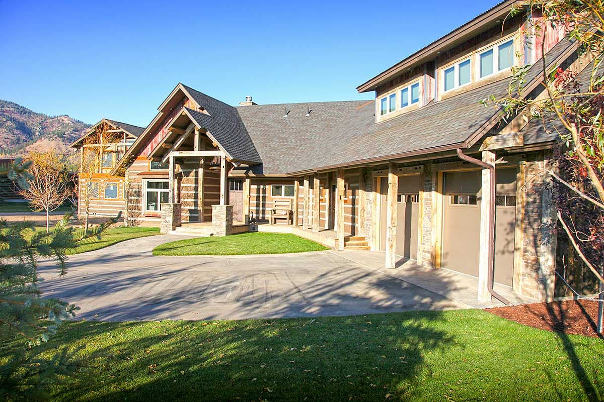 Log home exterior with multiple gables, exposed beams, covered front porch, and a three-bay garage.