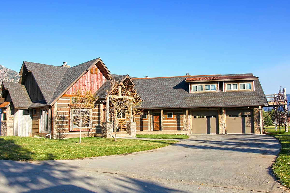 House plan exterior featuring a two-story log home with a gabled roof, log siding, a covered porch, and a three-car garage.