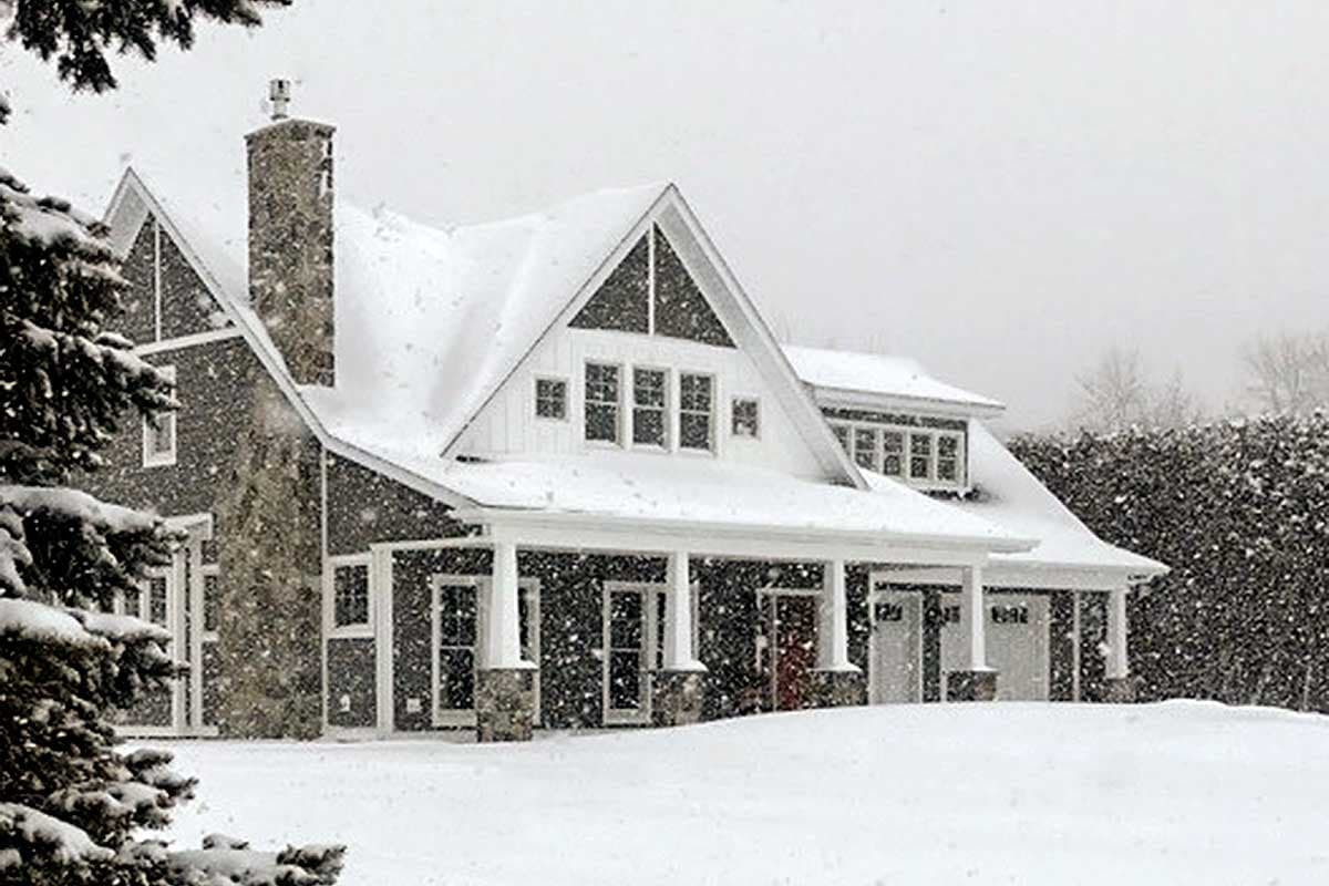 House plan exterior of a two-story Modern Farmhouse with a full-width front porch, stone chimney, and multiple gables.