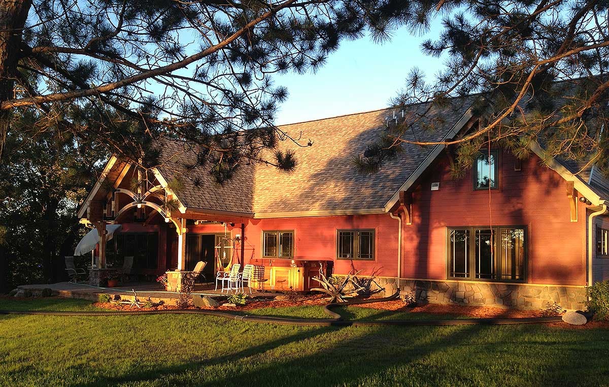 House plan exterior: Two-story Modern Farmhouse with covered porch, gables, dormers, and stone foundation.