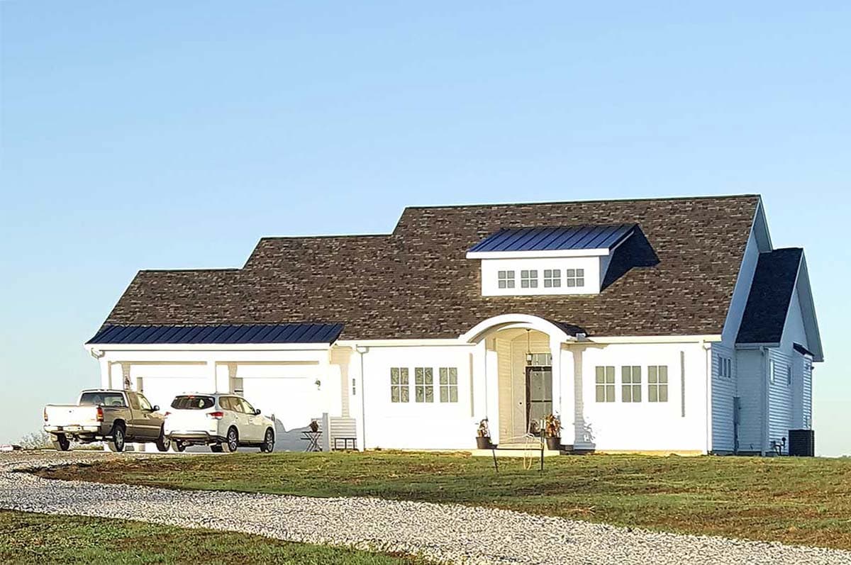House plan exterior: Modern farmhouse style, one story, with a three-car garage, gambrel rooflines, and arched entryway.