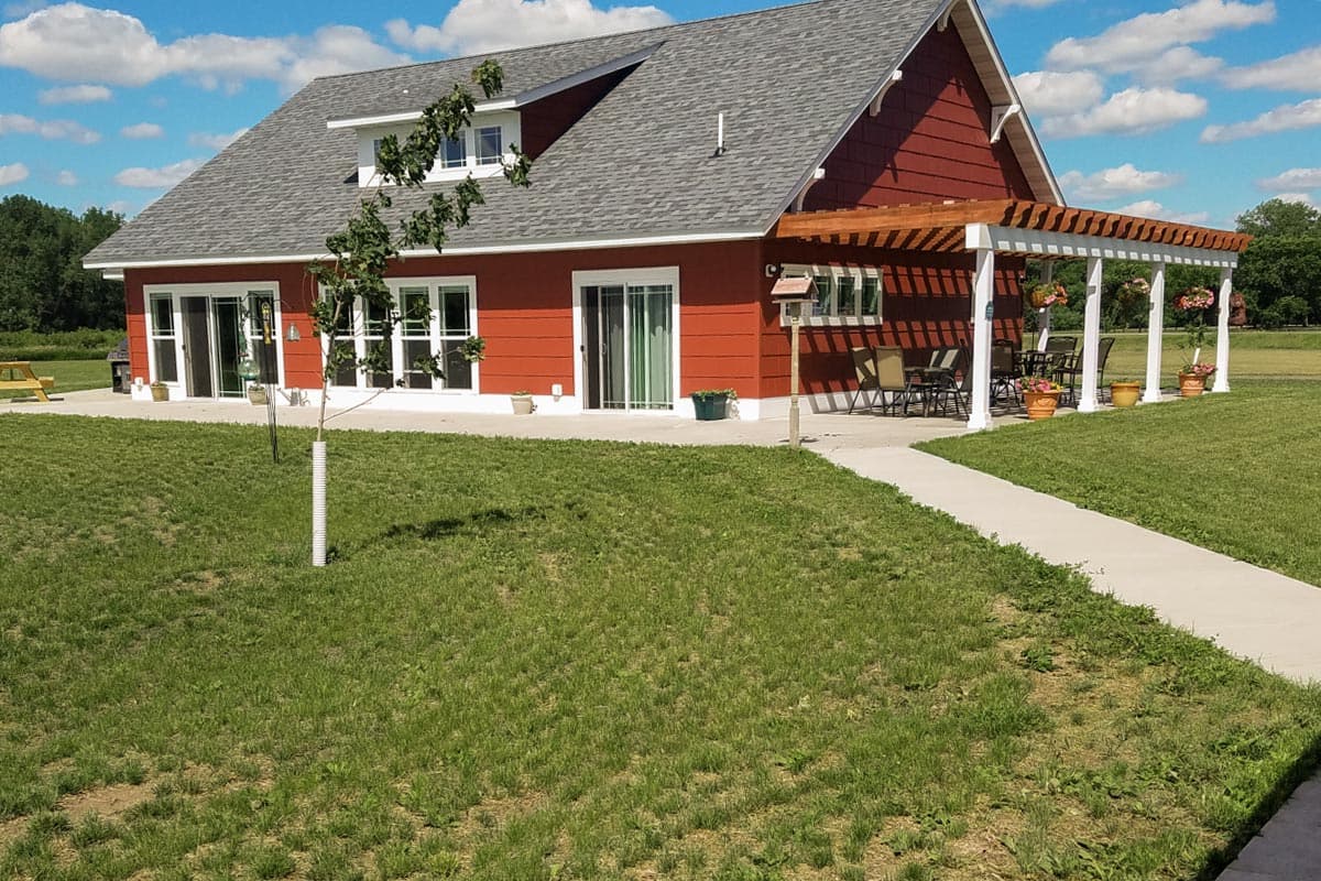 House plan exterior, two stories, gambrel roof, dormers, and covered pergola porch.