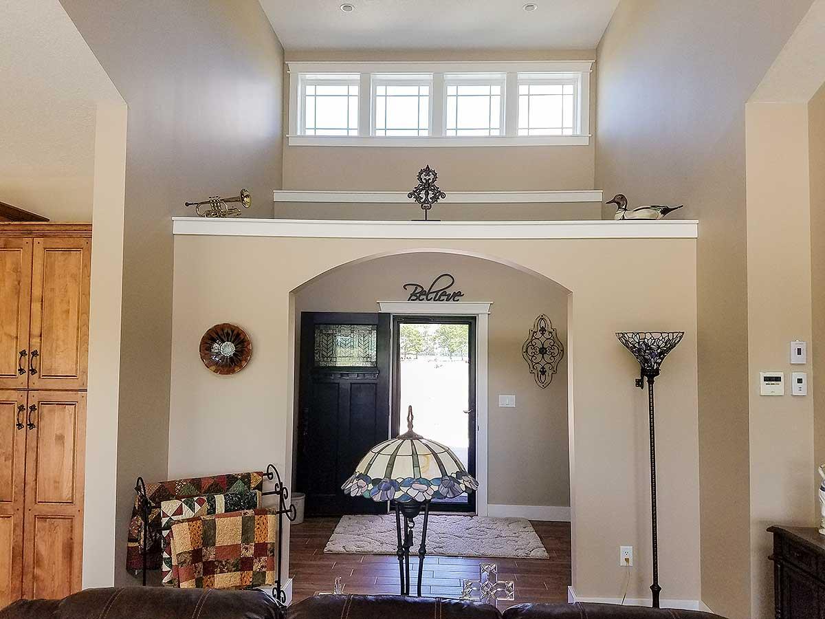Interior view of entryway with arched doorway, transom windows, and tall built-in cabinetry.