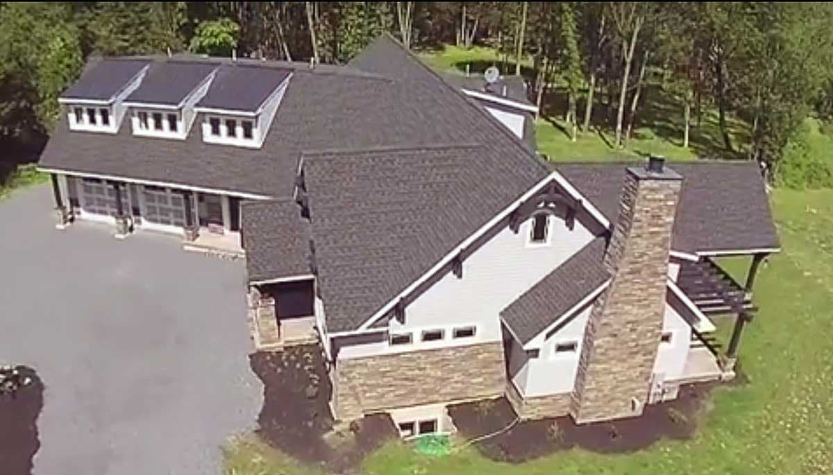House plan exterior: Modern Farmhouse style, two stories, with gabled dormers, stone foundation, and large chimney.