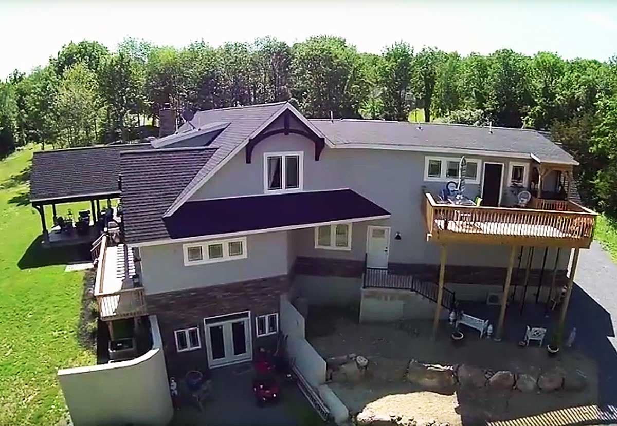 House plan exterior showing a two-story structure with a prominent gable, large deck, and covered patio.