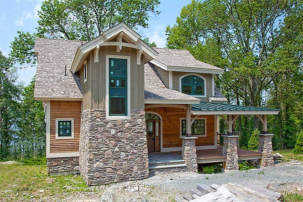 House plan exterior: Two-story home with stone foundation, wood siding, gables, dormers, and covered porch with stone columns.