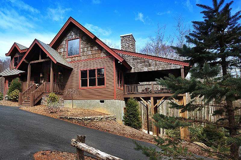 Craftsman house plan exterior with multiple gables, stone chimney, covered porch, and elevated deck.