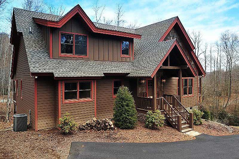 Two-story house plan exterior featuring a steep gable roof with exposed rafter tails, board and batten siding, and a covered front porch.