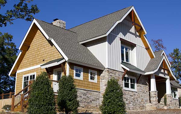 House plan exterior with wood shake siding, stone foundation, prominent gables, and a covered entrance porch.