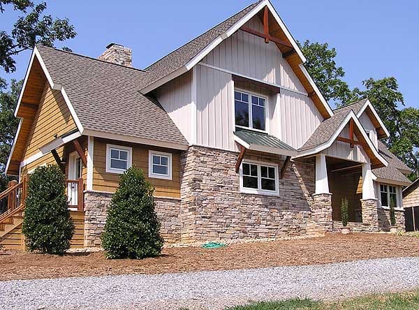 Craftsman house plan exterior with stone base, wood siding, multiple gables, exposed beams, and covered entry.
