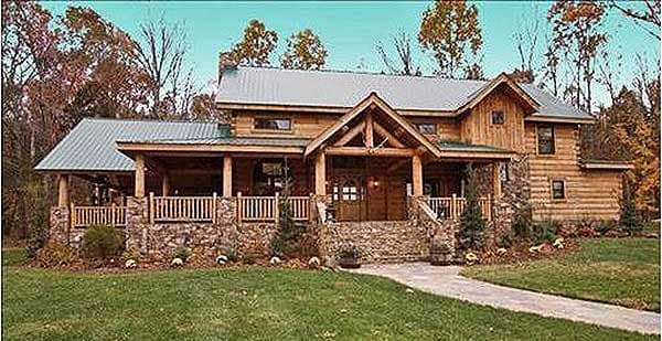Log home exterior with wraparound porch, stone accents, and metal roof. Two stories with prominent A-frame entrance.