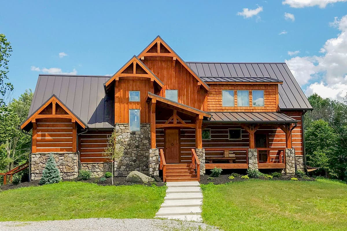 Log cabin house plan exterior with stone foundation, timber framing, covered porch, and metal roof.