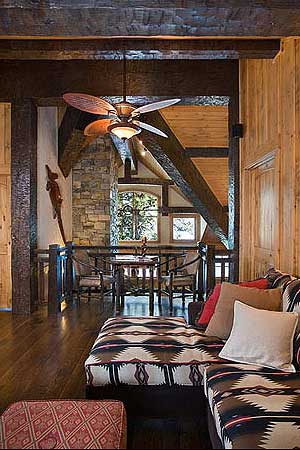 Interior view of rustic living area with exposed beams, stone accent wall, and patterned sectional.
