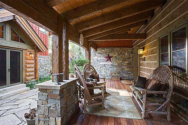 Covered porch with log siding, stone accents, rustic wood furniture, and exposed timber beams.