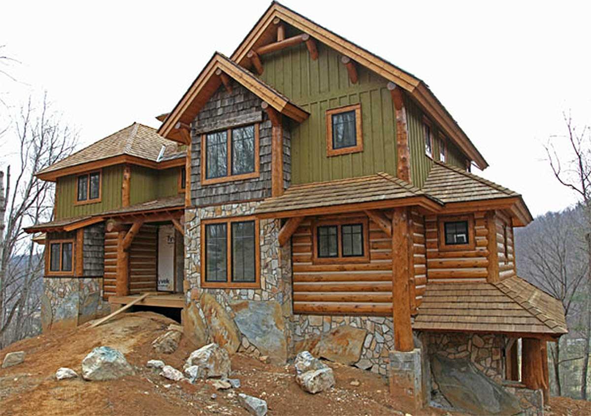 Log cabin style house plan exterior with stone foundation, wood shake siding, prominent gable roof, and timber framing.