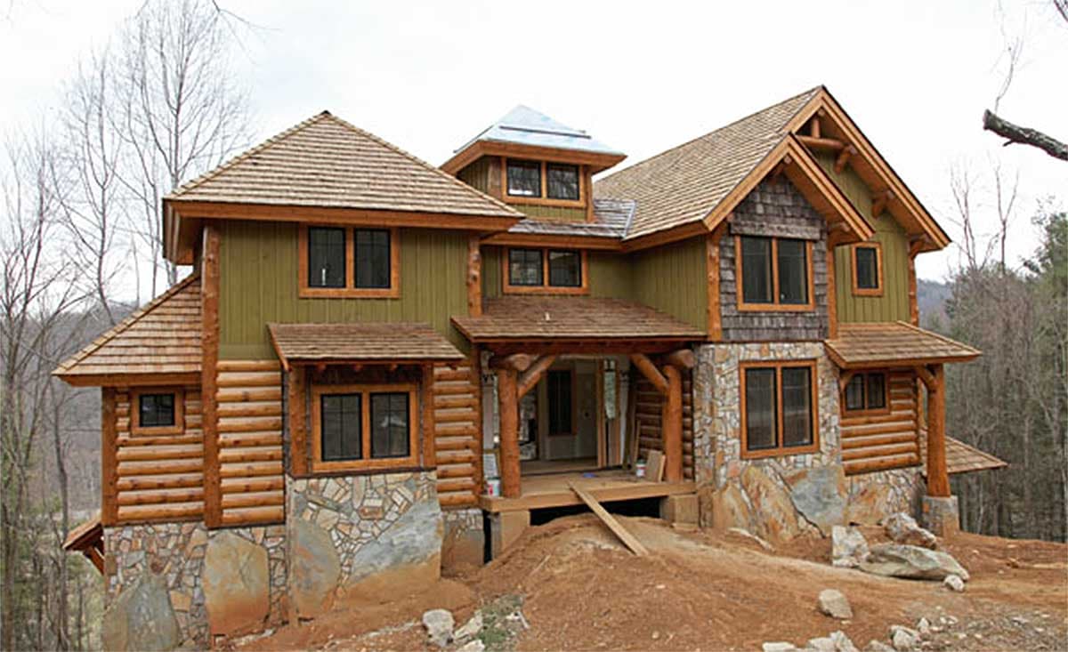 Log and stone house plan exterior featuring multiple gables, wood shake roofing, and a covered front porch with log supports.