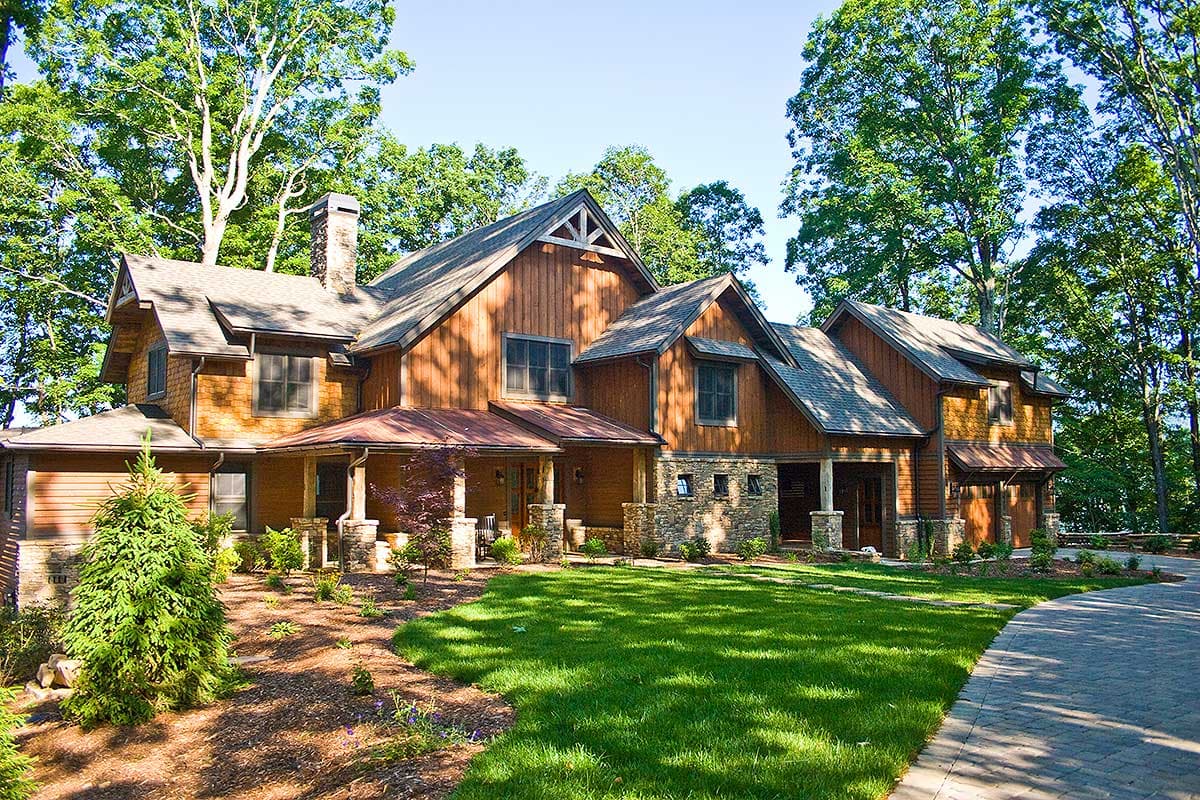Craftsman style house plan exterior with stone and wood siding, multiple gables, covered porches, and a three-car garage.