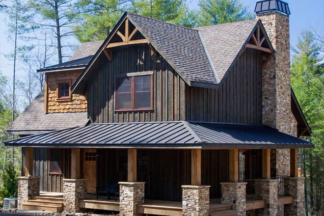 House plan exterior featuring a covered porch with stone and wood columns, gables with exposed rafter tails, and a prominent stone chimney.