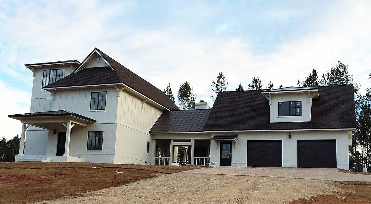House plan exterior: Two-story modern farmhouse with a covered entry, dormer, and three-car garage.