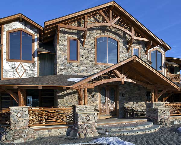 House plan exterior featuring rustic timber framing, stone facade, arched entryway, and decorative branch railings.