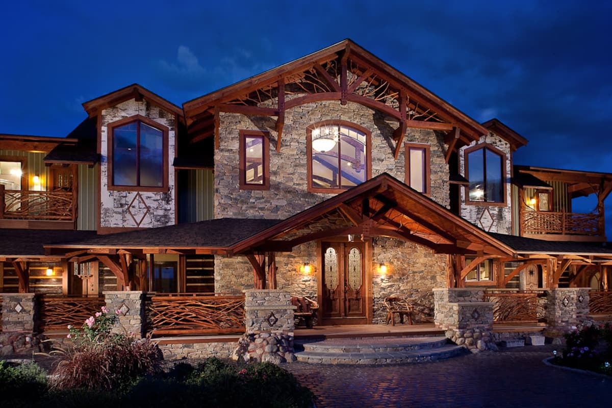 Log and stone house plan exterior with multiple gables, wood porches, and large windows.