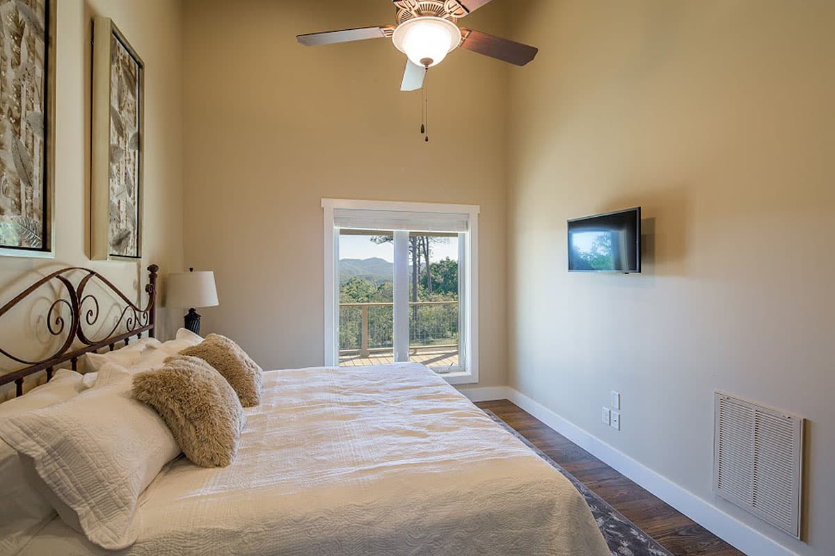 Bedroom with vaulted ceiling, large window with mountain view, and wall-mounted television.