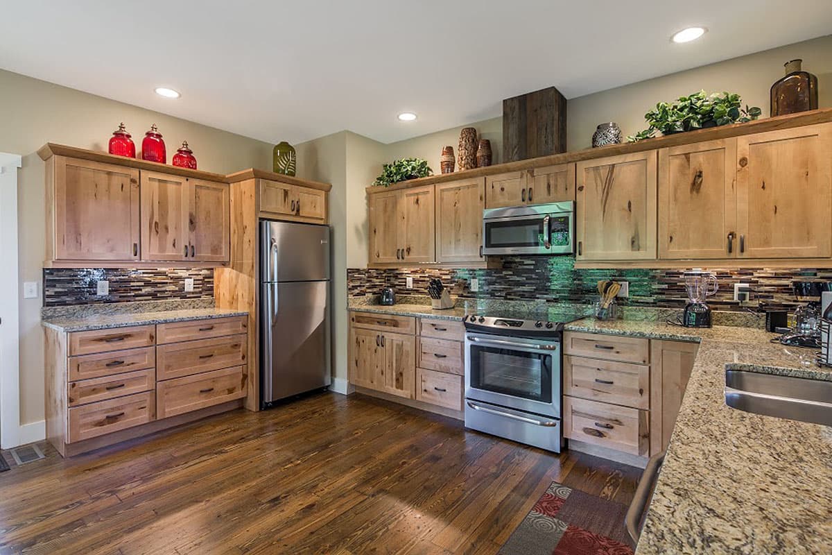 Kitchen featuring light wood cabinets, stainless steel appliances, granite countertops, and a mosaic tile backsplash.