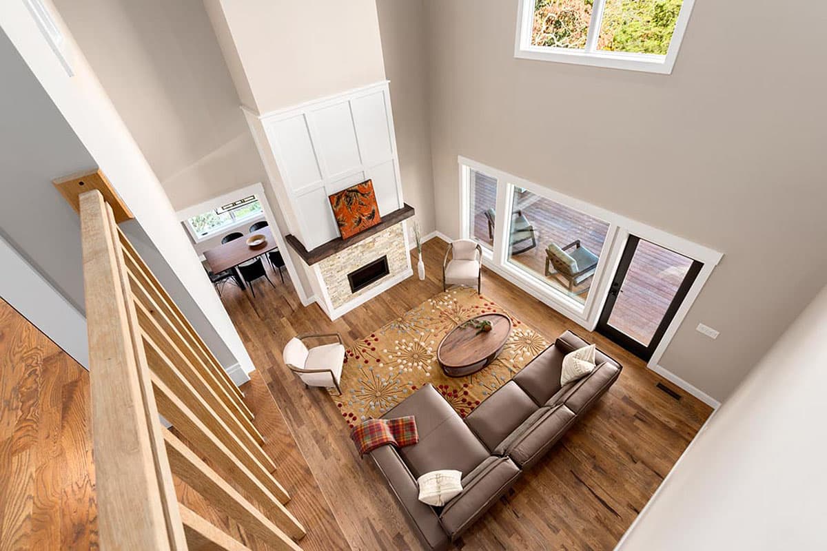 Great room interior view with vaulted ceiling, stone fireplace, sectional sofa, and large windows.