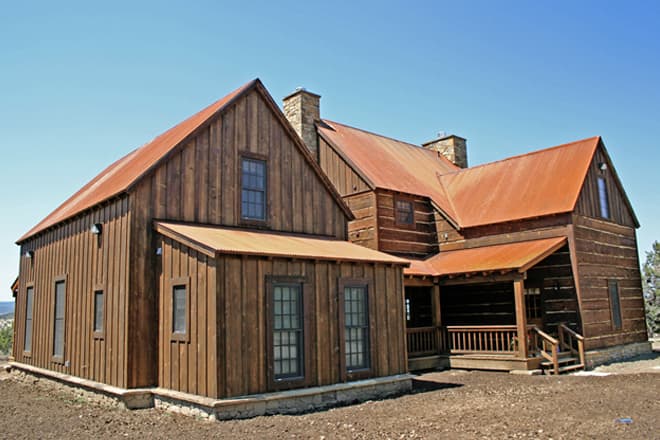 Log house plan exterior with vertical wood siding, metal roof, stone foundation, gables, dormers, and covered porch.