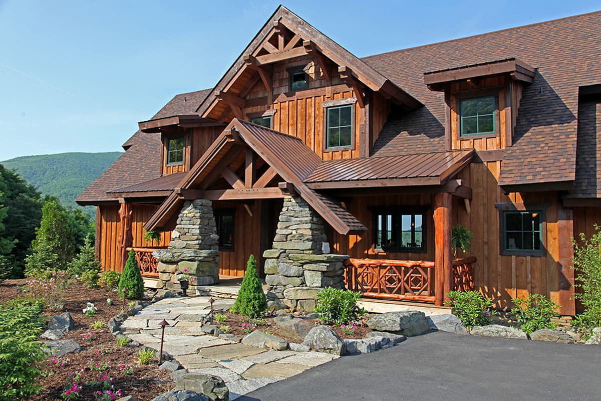 House plan exterior with Craftsman style, two stories, gabled roof, stone-clad porch supports, and decorative railing on porch.