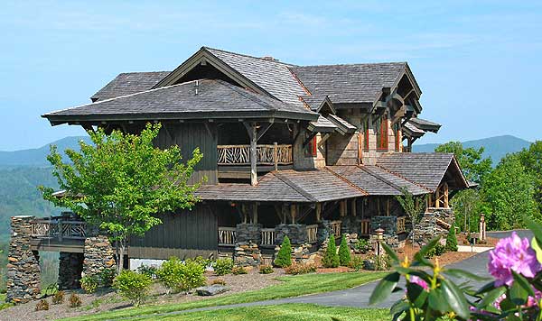House plan exterior: multi-story mountain lodge with stone foundation, deep eaves, and exposed timber framing.