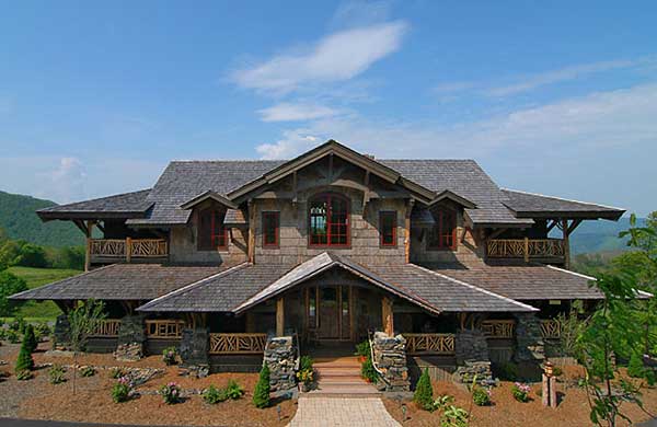 House plan exterior: Rustic style, multi-story home with prominent gables, extensive wood shake roofing, and covered balconies with stone supports.