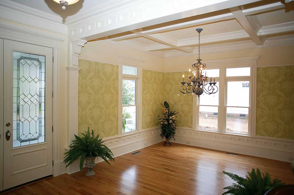 Interior view of a room with a coffered ceiling, chandelier, double-hung windows, and patterned wallpaper.