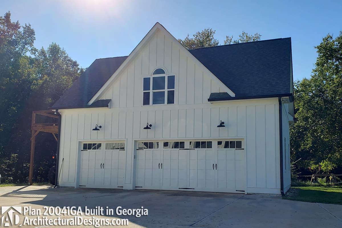 Modern Farmhouse house plan exterior with white board and batten siding, three garage bays, and a dormer window.