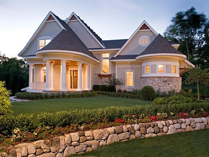 House plan exterior with curved porch, stone base turret, gables, and dormers.