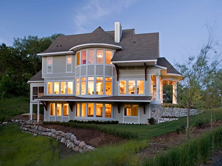 House plan exterior of a multi-story home featuring a curved bay of windows, covered porch with stone accents, and screened-in porch.